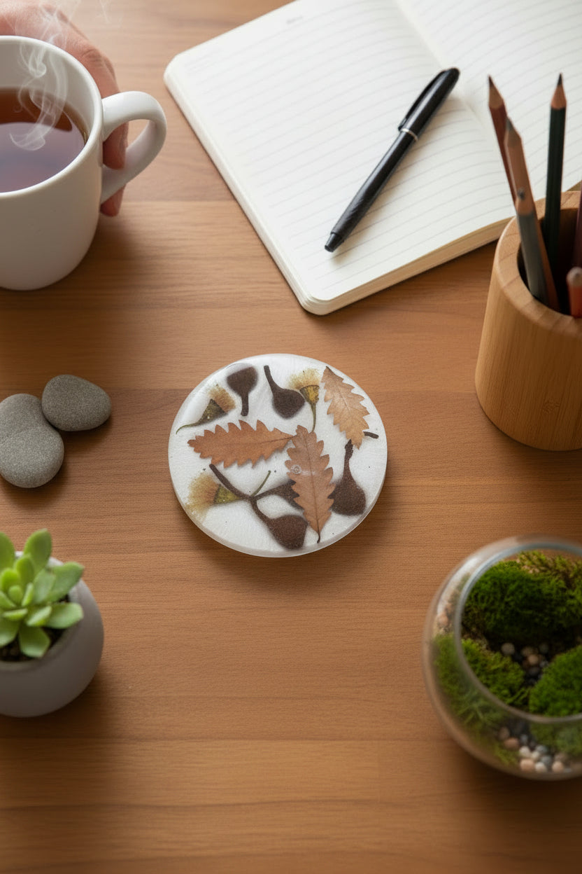Resin coaster showcasing real autumn leaves and yellow flowering gumnuts on a desk